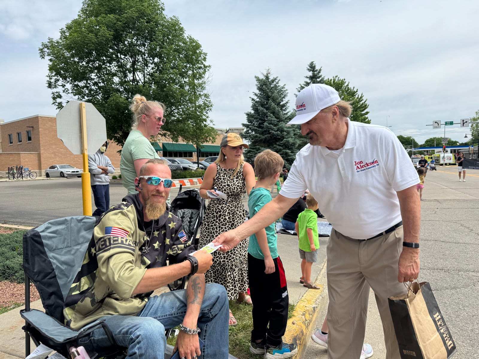 Jon Aleckson handing a campaign card to a veteran at a community event